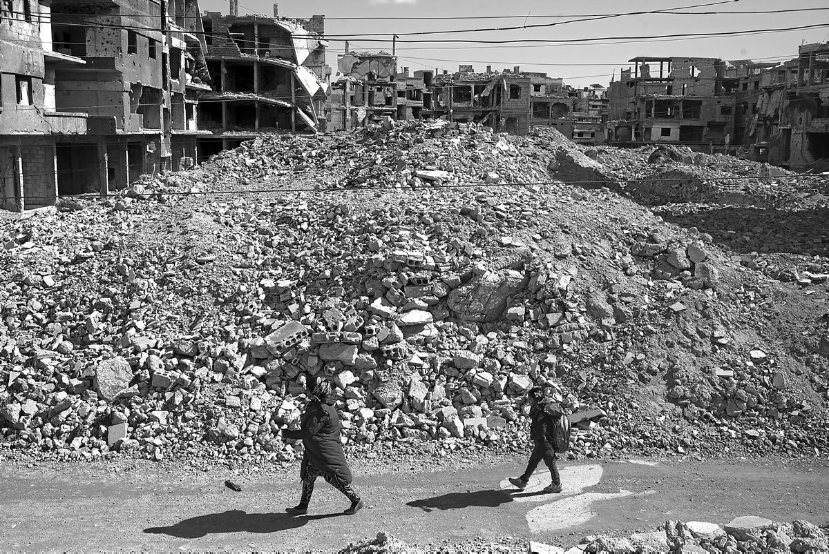 Una mujer acompaña a su hija a la escuela. En Yarmouk hace ocho años que no se dan clases, ya que las escuelas fueron destruidas.