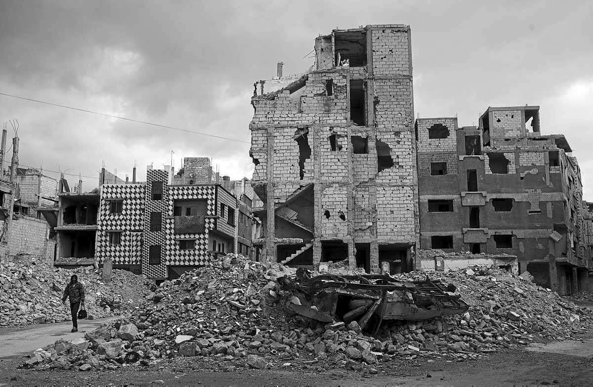 Escena de una persona andando por las calles de Yarmouk, todo rodeado de ruinas y escombros.