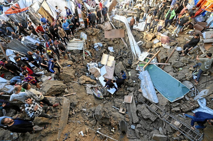 Búsqueda de cuerpos en el cráter de la escuela que refugiaba a desplazados en Bureij y fue atacada ayer por Israel.