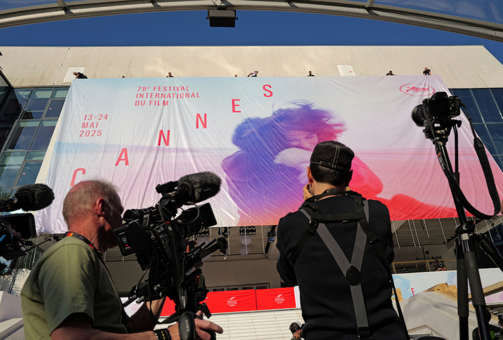 Trabajadores colocan una lona con la imagen oficial de la 78ª edición del Festival de Cine de Cannes. 