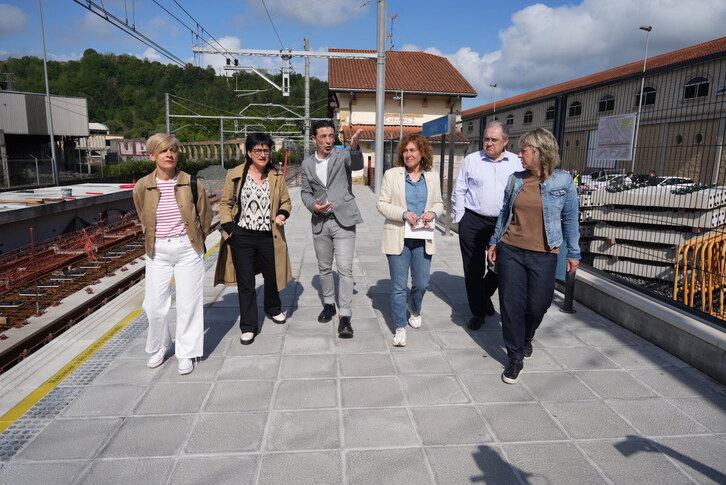 Las autoridades caminan por el andén, con la estación vieja al fondo.