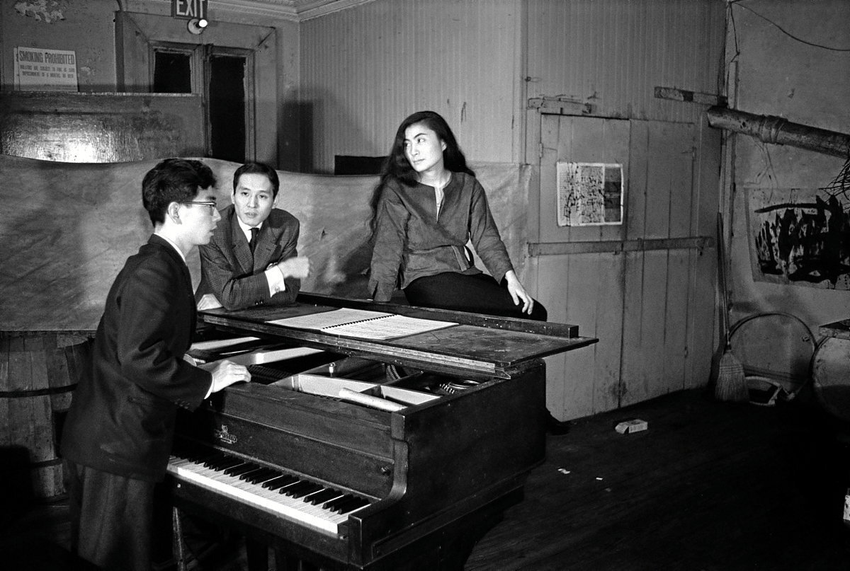 Sentada sobre el piano que toca su primer marido, Toshi Ichiyanagi, junto a otro compañero músico. (Minoru Niizuma y Yasuhiro Yoshioka)