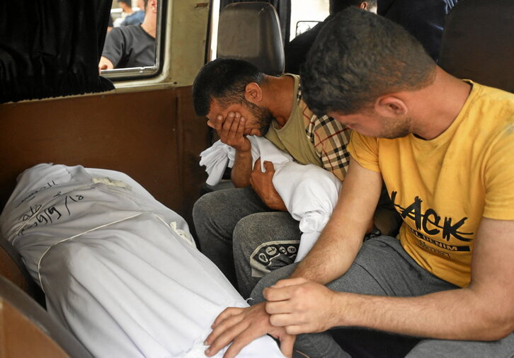 Un hombre llora ante los cuerpos de sus familiares muertos.