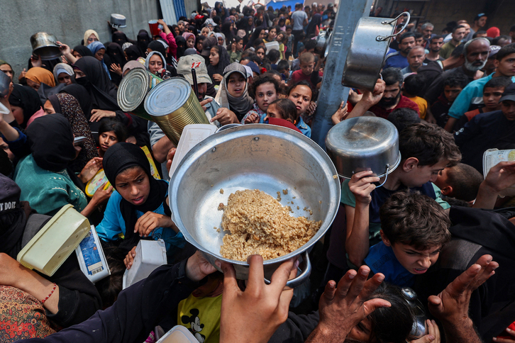 Palestinos se agolpan para recibir algo de comida en el campamento de Nuseirat.
