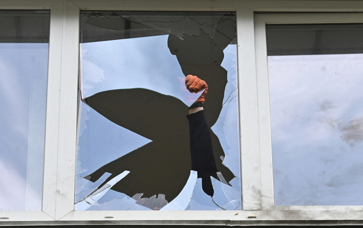 Retiran vidrios de un edificio afectado por el ataque con drones lanzado por Rusia.