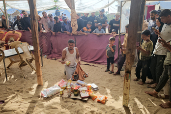 Un palestino abre la caja de comida que ha recibido en el reparto antes de que se suspendiera.