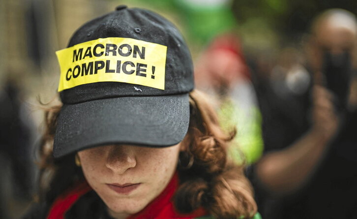 Una manifestante en París con una pegatina que acusa al presidente francés, Emmanuel Macron, de cómplice del genocidio.