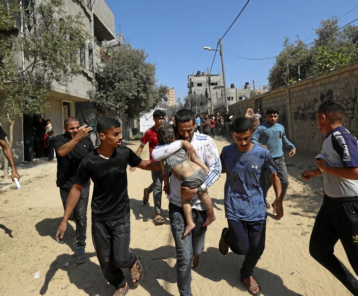 Palestinos trasladan a un niño herido en un bombardeo contra el campamento deAl-Bureij.