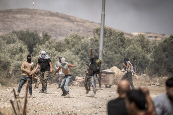 Colonos lanzan piedras contra residentes palestinos en Turmusaya, en uno de los pogromos de Cisjordania.