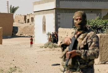 Varios niños observan a un integrante de las Fuerzas Democráticas Sirias durante una operación antiyihadista.