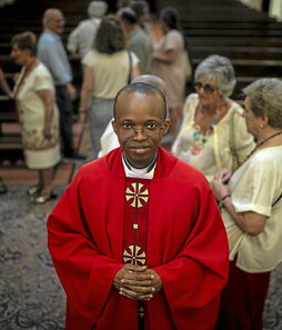 En la imagen que abre el reportaje, Job, el actual cura de la Iglesia de San Ignacio de Loyola.Arriba, uno de los carteles que anuncia la misa, en la entrada en la calle del Príncipe.