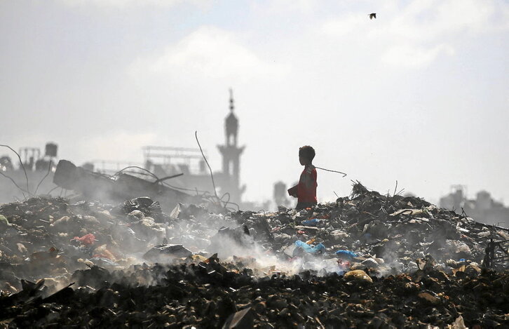 Un niño palestino busca entre la basura en el campo de refugiados en Bureij, en el centro de Gaza.
