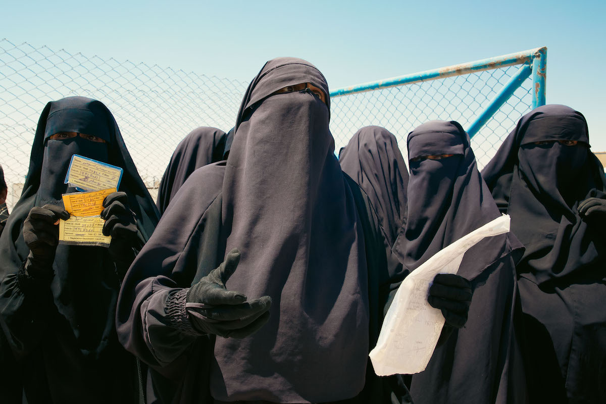 Mujeres iraquíes se preparan para subir a un autobús que las llevará de vuelta a su país, tras siete años en Al-Hol. (Laurent PERPIGNA)