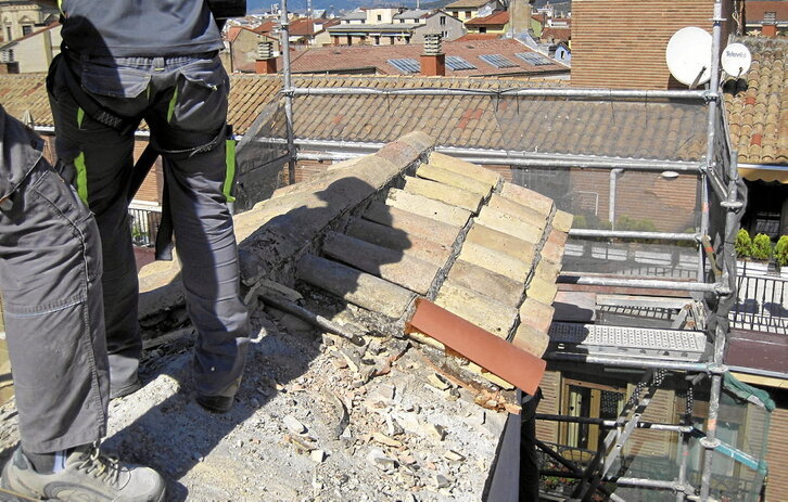 Dos trabajadores en labores de reparación de un tejado.