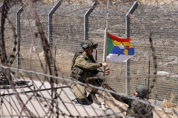 Un militar israelí coloca la bandera rusa en la antena de su tanque