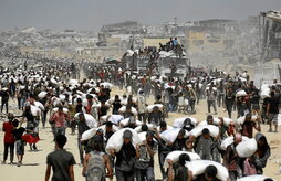 Palestinos caminan con sacos de harina cerca de Jabalia, después de que camiones con ayuda entraran en la Franja.