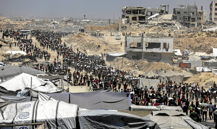 Palestinos cargan sacos de harina recogidos en el reparto de un convoy en Yabalia.