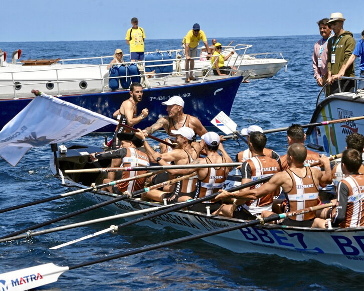 Zierbenako arraunlariak, pozez zoratzen, bandera hartuta.