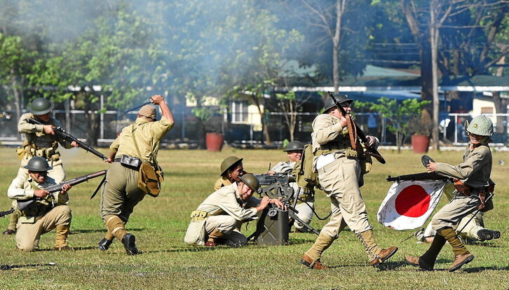 A la izquierda, una mujer observa la Cúpula de la Bomba Atómica, en el centro de Hiroshima. Abajo, recreación de la batalla de Manila a cargo de la Sociedad de Historia Viva.