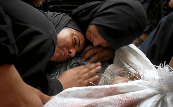 Emakume bat, laguntza bila joandako senide baten gorpu gainean negarrez.