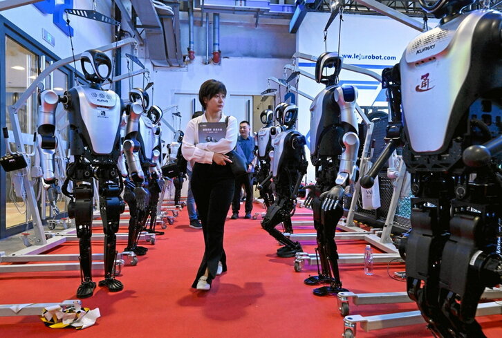 Una mujer camina entre robots durante la Conferencia Mundial de Robótica.