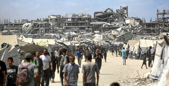 Palestinos caminan por una calle de Ciudad de Gaza, entre tiendas de campaña y edificios destruidos por el Ejército israelí.