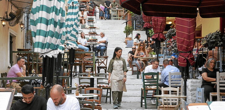 Varios turistas descansan sentados en la terraza de un bar en el histórico barrio ateniense de Plaka.