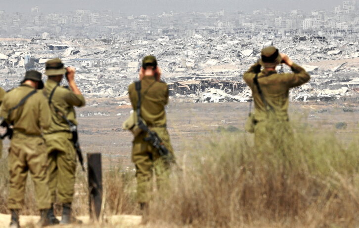 Soldados israelíes observan los edificios destruidos de Gaza.