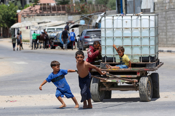 Un hombre y varios niños empujan un carro con un tanque de agua en el campo de regfugiados del Al-Burej.