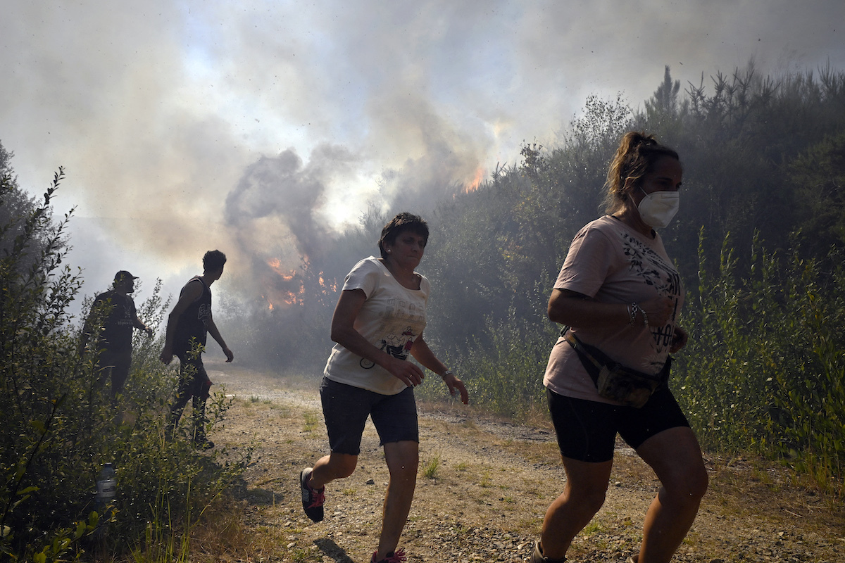Vecinos huyen de las llamas el pasado viernes en Melón (Ourense). (Miguel Riopa | AFP)