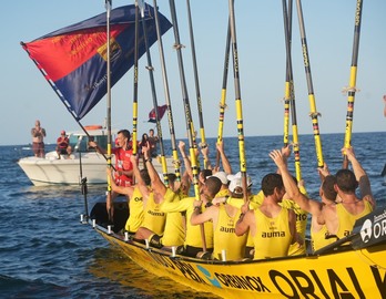 Gorka Aranbarri ondea la bandera mientras su tripulación alza los remos.