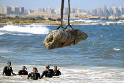 Una grúa saca del agua una estatua, en la bahía de Alejandría.