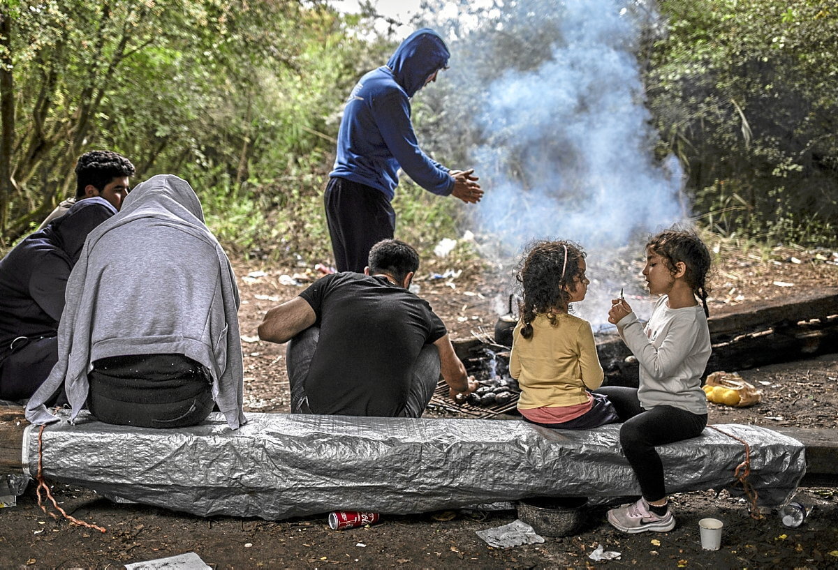 Una familia prepara la comida en el campamento de Loon- Plage; miles de personas esperan en este campamento el día que cruzarán el Canal. (Sergi Cámara)