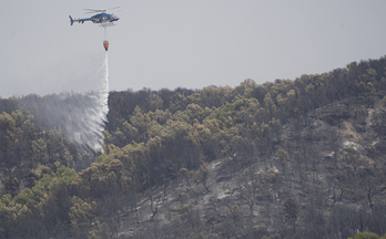 Un helicóptero arroja agua en la zona afectada por el incendio de Zarrakaztelu