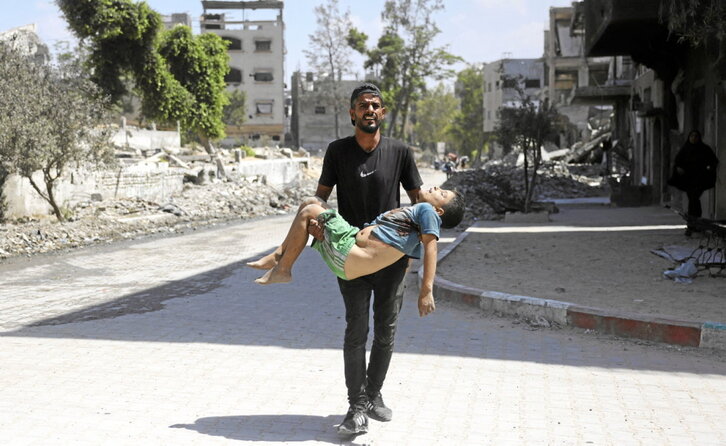 Un hombre carga el cuerpo de un menor al que Israel mató cuando huía de su casa en Jabalia.