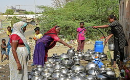 Imagen de archivo de una joven que vierte agua potable en un recipiente en las afueras de la ciudad india de Ahmedabad.