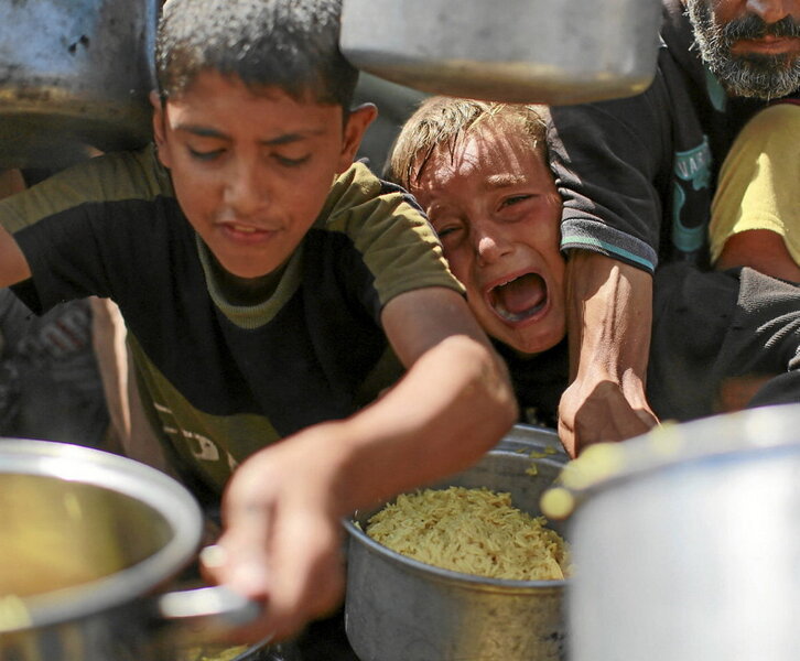Niños palestinos intentan conseguir comida en un comedor social al oeste de Ciudad de Gaza.