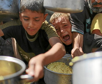 Niños palestinos intentan conseguir comida en un comedor social al oeste de Ciudad de Gaza.