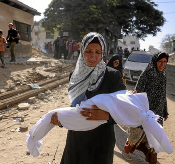 Una mujer carga el cuerpo de un niño frente al hospital Al-Shifa, en Ciudad de Gaza.