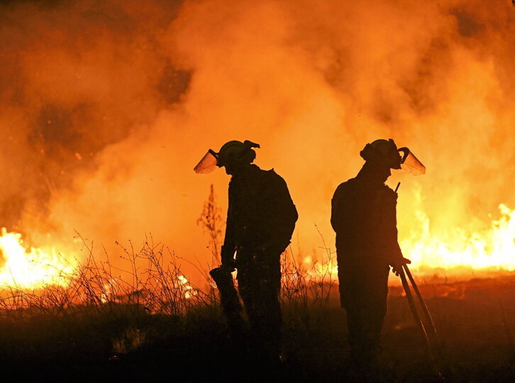 Abajo, dos bomberos trabajan en labores de extinción. En la página siguiente, vecinos tratan de apagar las llamas en distintos incendios de Ourense.
