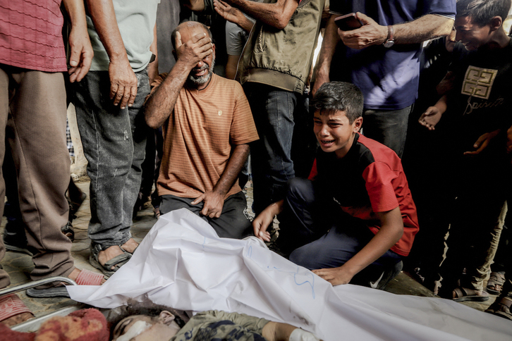 Familia bat hildako ume baten gorpuaren inguruan, abuztuaren 16an, Gaza hirian.