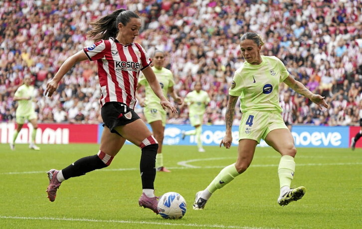 Jone Amezaga avanza con el balón junto a Mapi León.
