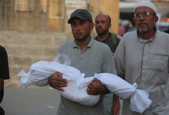 Un hombre lleva el cadáver de un niño muerto en un ataque israelí.
