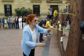 Una ciudadana coloca una flor en la estatua de la calle Ijentea de Donostia.