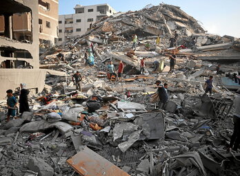 Palestinarrek Gazako eraikin baten kalteak ikuskatzen dituzte, Israelen eraso baten ondoren.