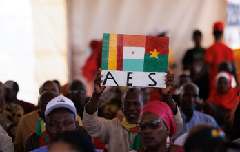 Un hombre levanta un cartel con las banderas de los tres países del AES, en una ceremonia en Kangaba, Mali.