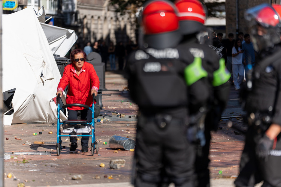 Una mujer, ajena a las trifulcas, pasea entre manifestantes y agentes de la Ertzaintza.