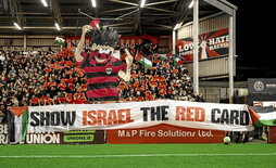 Abajo, la hinchada de los Bohs despliega una pancarta contra Israel.