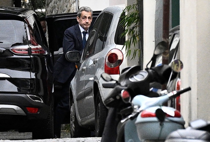 Sarkozy sale de un vehículo camino a su casa después de hablar con los fiscales sobre el inicio de su condena.