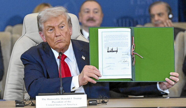 Donald Trump muestra el documento del acuerdo firmado.